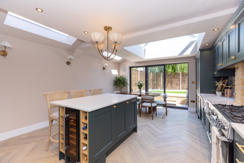 Kitchen island with built-in wine fridge and dual skylights, herringbone flooring leading to a dining nook