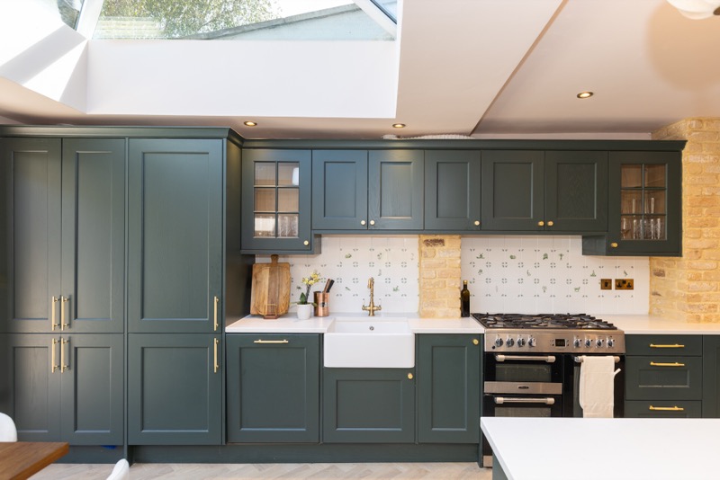 Belfast sink and range cooker framed by a skylight with bespoke cabinetry and exposed brick