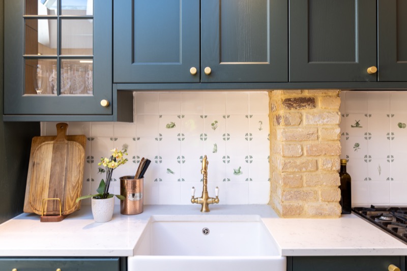 Belfast sink with brass tap, copper utensil pot and hand-painted ceramic tile splashback