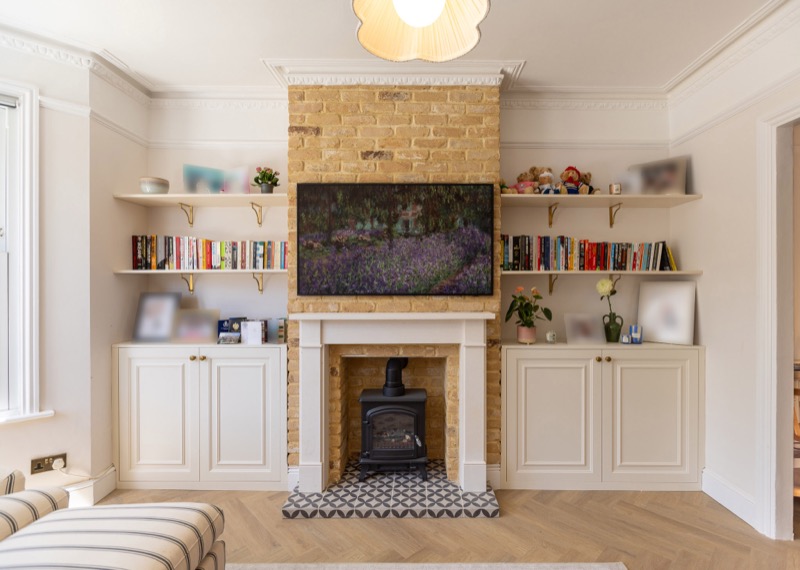 Symmetrical alcove cabinetry flanking an exposed brick fireplace with mounted artwork above a woodburner