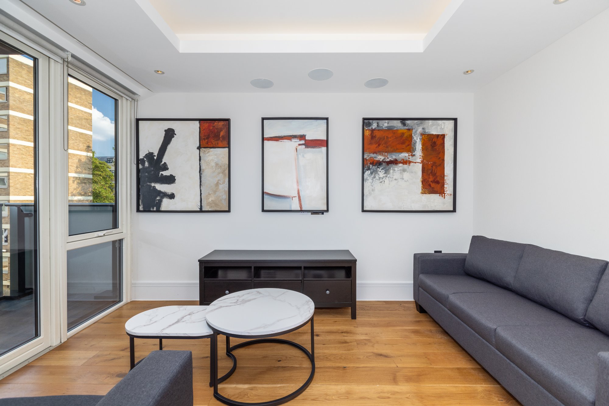 Living room with abstract art triptych and grey sofas