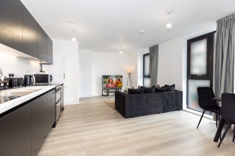 Open-plan apartment with dark kitchen, charcoal sofa and light oak flooring