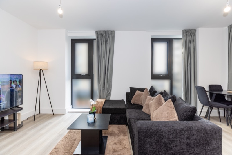 Contemporary living room with charcoal sofa, beige cushions and tripod lamp