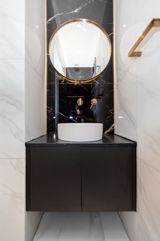 Modern vanity with gold-framed mirror and vessel sink